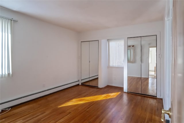 unfurnished bedroom with a baseboard radiator and wood-type flooring