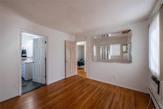 empty room with wood-type flooring and baseboard heating