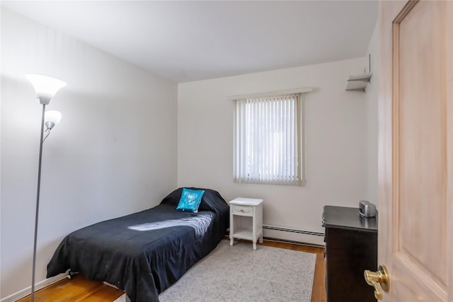 bedroom featuring baseboard heating and light hardwood / wood-style flooring