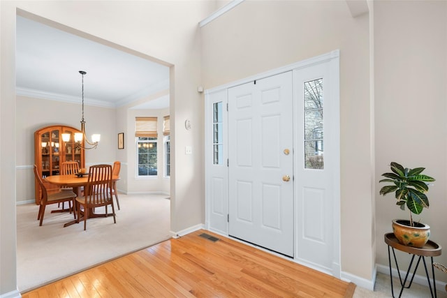 entrance foyer featuring crown molding, a chandelier, and hardwood / wood-style floors