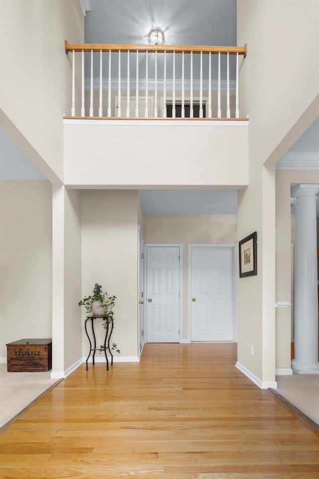 entrance foyer with a towering ceiling, ornate columns, and hardwood / wood-style flooring