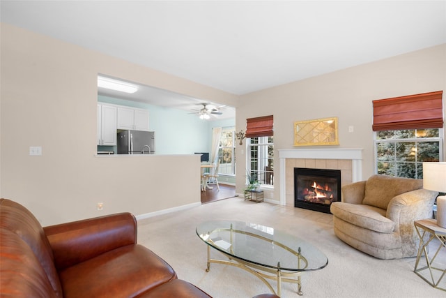 carpeted living room featuring ceiling fan and a tile fireplace