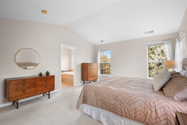 bedroom with ensuite bathroom, lofted ceiling, and light carpet