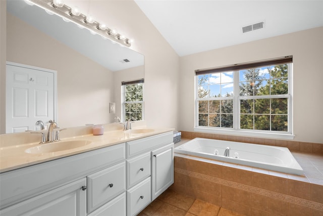 bathroom featuring vanity, tiled tub, tile patterned floors, and lofted ceiling