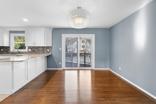 kitchen with tasteful backsplash, white cabinets, and light stone counters