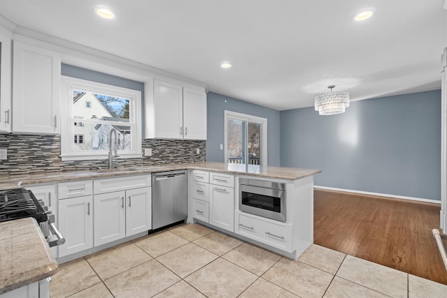 kitchen featuring white cabinetry, appliances with stainless steel finishes, light tile patterned floors, and kitchen peninsula