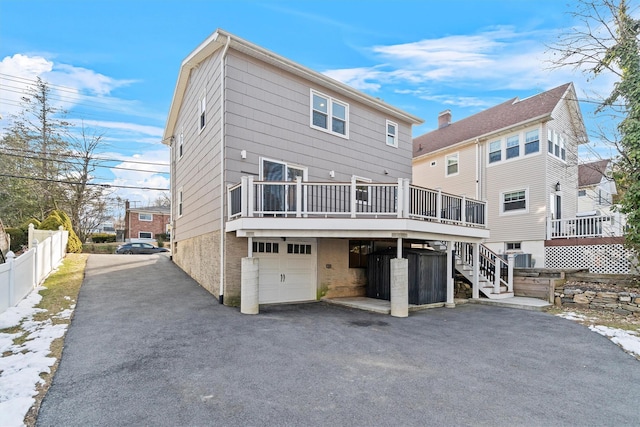 rear view of house featuring a wooden deck and a garage