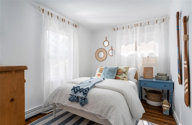 bedroom with multiple windows, dark hardwood / wood-style flooring, and baseboard heating