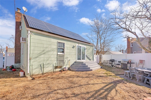 back of house featuring solar panels