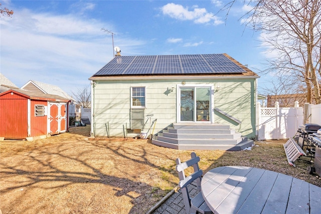 rear view of property with a storage unit and solar panels