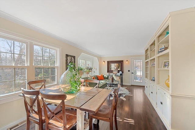 dining room featuring dark wood-style floors, a healthy amount of sunlight, ornamental molding, and visible vents