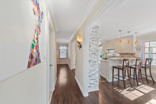 hall with ornamental molding, dark wood finished floors, and baseboards