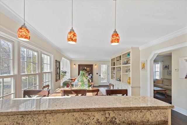 kitchen featuring dark wood-style floors, baseboards, light stone countertops, and crown molding