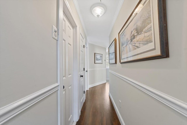 hall featuring dark wood-style floors, crown molding, and baseboards