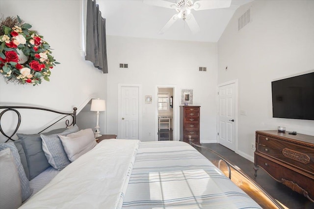 bedroom featuring a high ceiling, visible vents, baseboards, and wood finished floors