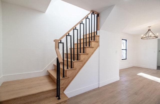 stairs with hardwood / wood-style floors and a chandelier