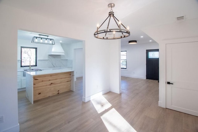 unfurnished dining area featuring a wealth of natural light, a chandelier, and light wood-type flooring