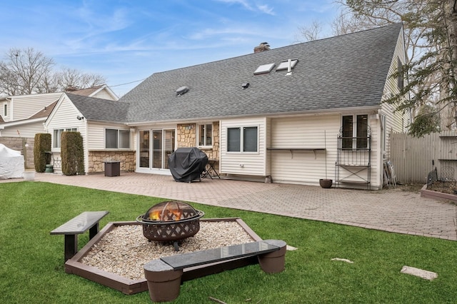 rear view of property with a patio, a fire pit, and a lawn