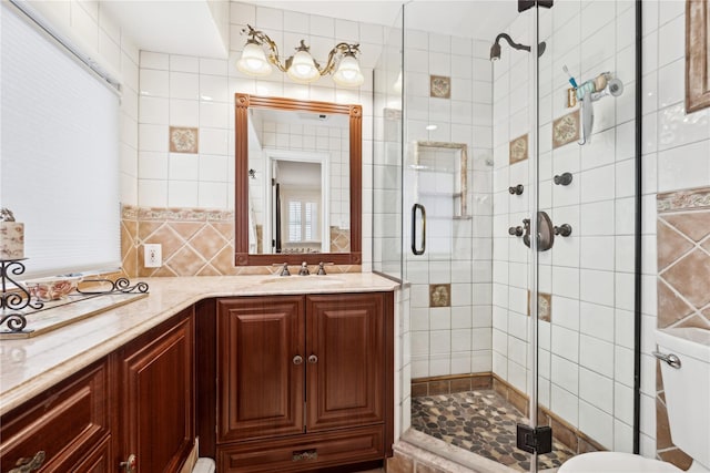 bathroom with toilet, tile walls, vanity, and walk in shower