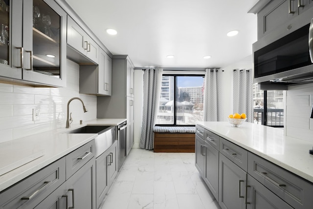 kitchen with stainless steel appliances, tasteful backsplash, gray cabinets, and sink