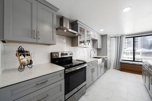 kitchen featuring wall chimney exhaust hood, sink, gray cabinetry, appliances with stainless steel finishes, and decorative backsplash