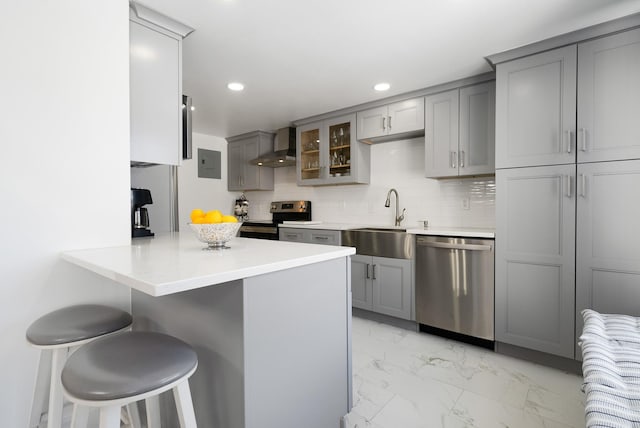 kitchen featuring a breakfast bar, sink, kitchen peninsula, stainless steel appliances, and wall chimney range hood