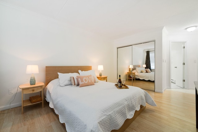 bedroom featuring hardwood / wood-style flooring, crown molding, baseboard heating, and a closet