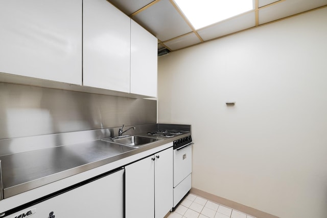 kitchen with sink, light tile patterned floors, white cabinets, white range, and a drop ceiling