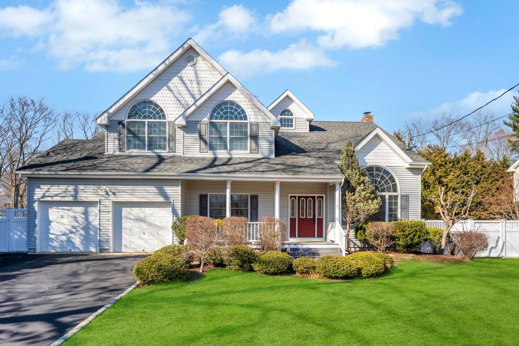 view of front facade featuring a front yard, a porch, driveway, and fence