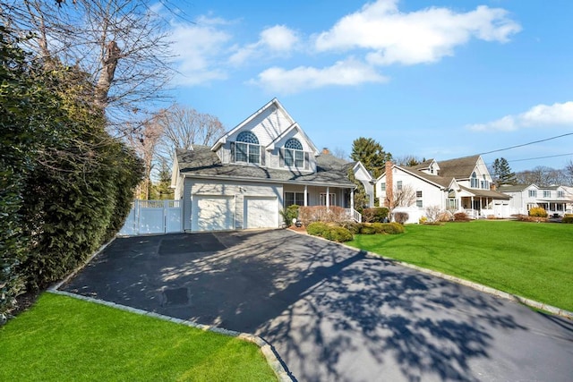 view of front facade with aphalt driveway, a residential view, a front yard, covered porch, and a gate