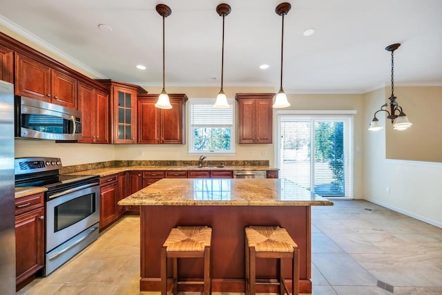 kitchen featuring a breakfast bar, pendant lighting, a sink, appliances with stainless steel finishes, and crown molding