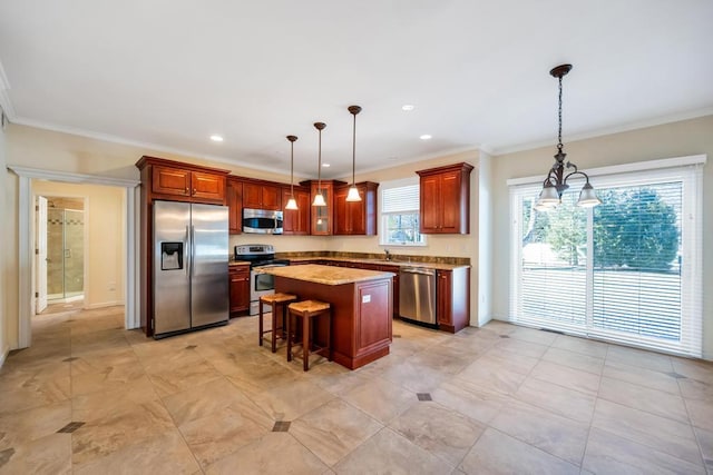 kitchen featuring a kitchen island, pendant lighting, ornamental molding, appliances with stainless steel finishes, and a kitchen breakfast bar