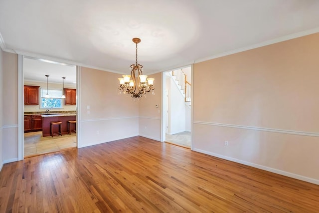 unfurnished dining area with crown molding, baseboards, stairway, light wood-style flooring, and an inviting chandelier