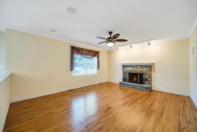 unfurnished living room with baseboards, light wood-style floors, ornamental molding, and a fireplace