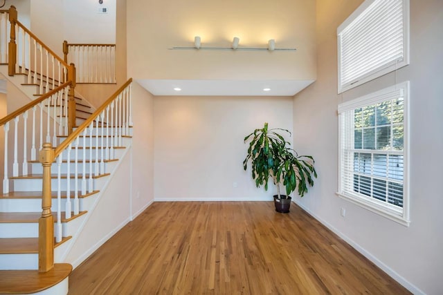 interior space with baseboards, stairway, recessed lighting, a towering ceiling, and wood finished floors