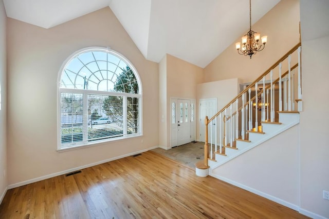 foyer entrance featuring a notable chandelier, stairs, baseboards, and wood finished floors