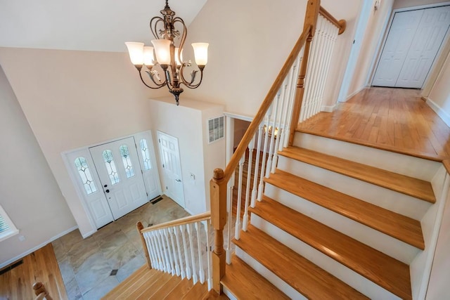 foyer with visible vents, baseboards, a notable chandelier, and stairs