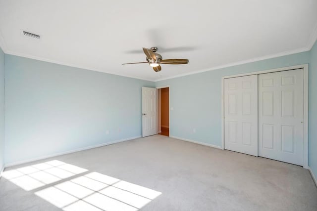 unfurnished bedroom with visible vents, a closet, crown molding, and carpet flooring