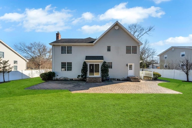 back of house with entry steps, a chimney, a fenced backyard, a yard, and a patio area