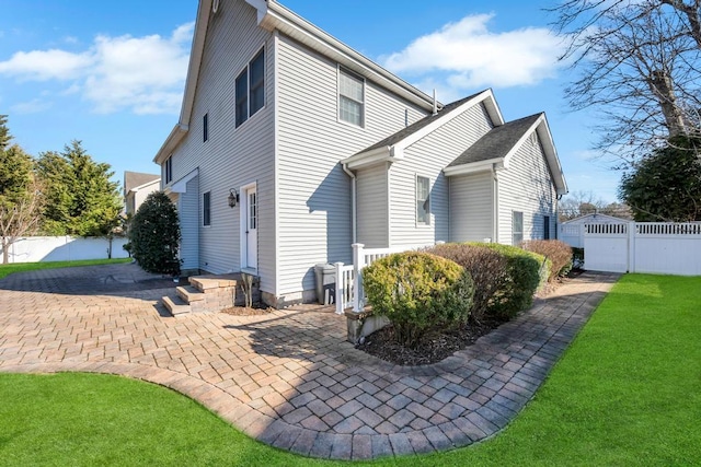 rear view of house featuring a gate, a lawn, a patio, and fence