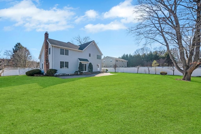 rear view of house with a fenced backyard, a patio area, a chimney, and a yard