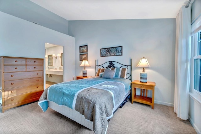 carpeted bedroom featuring lofted ceiling and ensuite bath