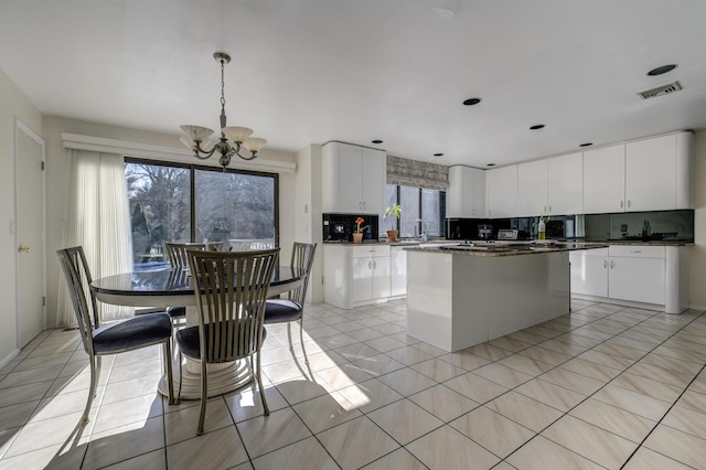 kitchen featuring white cabinetry, backsplash, a center island, and pendant lighting