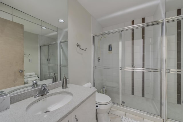 bathroom with vanity, a shower with shower door, tile patterned floors, and toilet