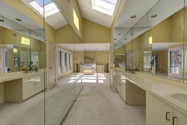 bathroom with vanity, concrete flooring, a skylight, and high vaulted ceiling