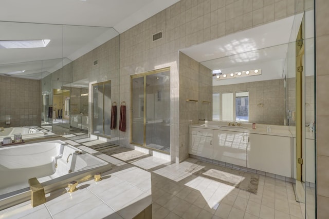 bathroom featuring tile patterned floors, vanity, plus walk in shower, and tile walls