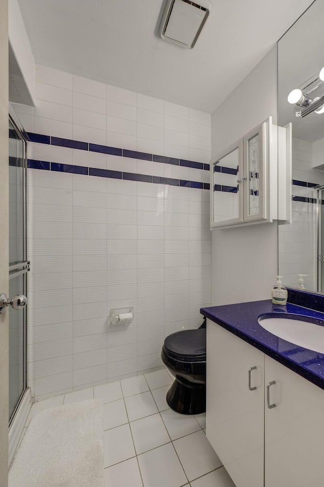 bathroom with tile walls, tile patterned flooring, vanity, walk in shower, and toilet