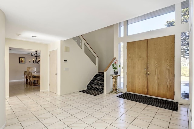 entrance foyer with light tile patterned floors, stairway, and an inviting chandelier