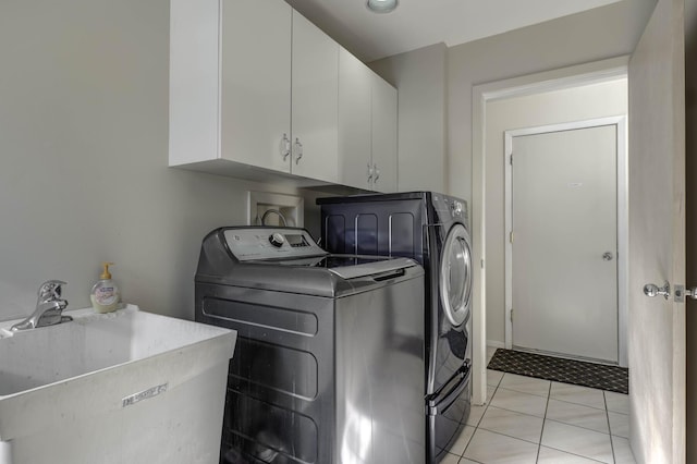 laundry area featuring light tile patterned floors, washing machine and dryer, a sink, and cabinet space