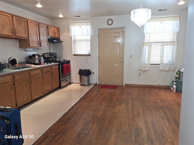 kitchen featuring sink, hanging light fixtures, stainless steel range with gas stovetop, and a healthy amount of sunlight